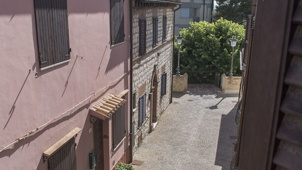 A narrow cobblestone street flanked by buildings with shutters and a small tree. - S187 - Sirolo, delightful sky-earth house in the alleys (Sirolo)
