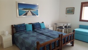 Un dormitorio con cama, mesita de noche, mesa y silla.