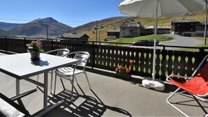 A balcony with a table and chairs, a potted plant, and a white umbrella. - Lovely apartment for 4 guests with WIFI, TV and terrace (Baite)