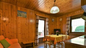 A cozy wooden cabin interior with a dining area, a sofa, and a television. - Lovely apartment for 4 guests with WIFI, TV and terrace (Baite)