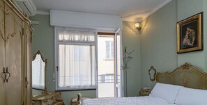 A bedroom with a large bed, a wardrobe, a mirror, and a window with curtains.