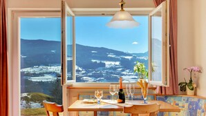 A cozy room with a large window offering a scenic view of snow-covered hills. - Nice apartment for 4 people with pool, WIFI, TV, terrace and pets allowed (Villandro)
