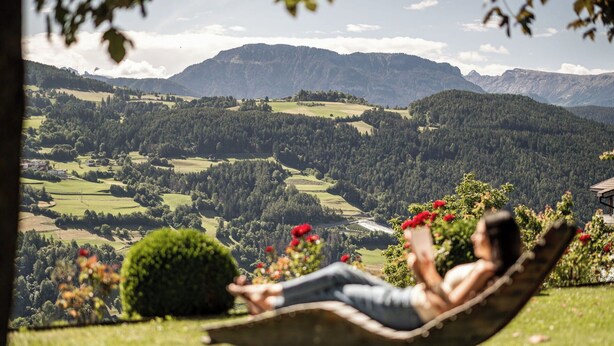 Una persona descansando en una hamaca con una vista panorámica de un paisaje montañoso.