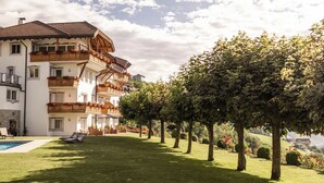 Un hotel de varios pisos con balcones, piscina y un jardín bien cuidado.
