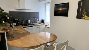 Una cocina moderna con una isla de madera, sillas blancas, un árbol de Navidad y un cuadro en la pared.