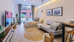 A modern living room with a sofa, a TV, a dining area, and a balcony with a view. - Stratus Loft Gran Canaria, elegance on Las Canteras beach. (Las Palmas de Gran Canaria)
