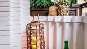 A balcony with a white brick wall, a green plant wall, a wicker lantern, and a green vase. - Stratus Loft Gran Canaria, elegance on Las Canteras beach. (Las Palmas de Gran Canaria)