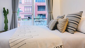 A bed with a striped blanket, two pillows with a striped pattern, and a cactus plant. - Stratus Loft Gran Canaria, elegance on Las Canteras beach. (Las Palmas de Gran Canaria)
