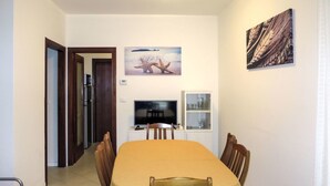 Un coin repas comprenant une table et des chaises, un téléviseur et un meuble.