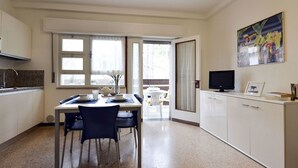 Una cocina compacta con comedor, televisor y un cuadro en la pared.