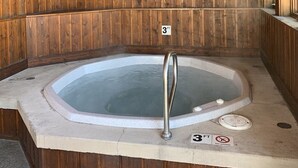 En stuga av trä med ett bubbelbad, ett träpanelat tak och en skylt som visar att bubbelbadet är 90 centimeter djupt.