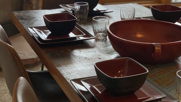 Ett matbord dukat med skålar och glas, en steneldstad och utsikt över ett snötäckt område utomhus.
