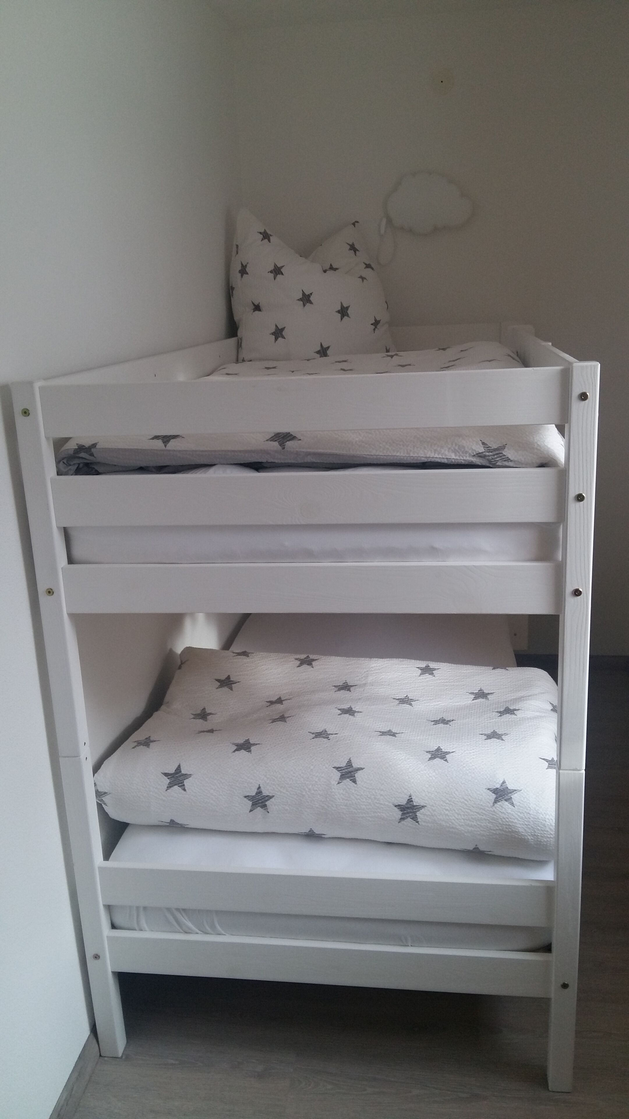 Una cama litera blanca con ropa de cama estampada de estrellas.