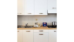 Een keuken met witte kastjes, een roestvrijstalen spoelbak en een fornuis.