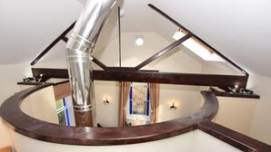 Eine Wendeltreppe mit hölzernem Geländer und einem Metallrohr, das hindurchführt.