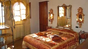 Ein Schlafzimmer mit Bett, einem Holzschrank, einem Spiegel und einem Fenster mit Vorhängen.