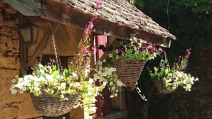 En rustik stenbyggnad med hängande blomkorgar.