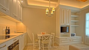 Una cocina moderna con armarios blancos, una mesa de comedor con sillas, una araña y electrodomésticos integrados.