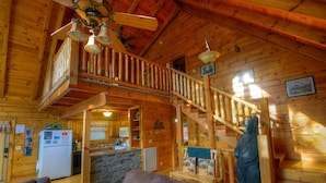 Ein Holzblockhaus-Innenraum mit Treppe, Küchenzeile und einer Bärenstatue.