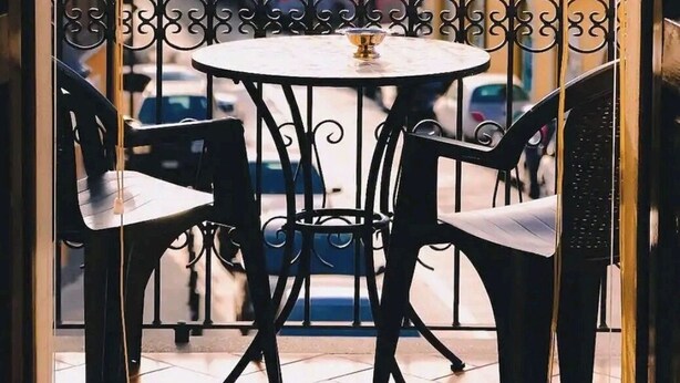 Un balcón con una mesa redonda y cuatro sillas, con vista a una zona residencial con edificios de colores.