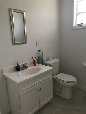 Un baño con lavamanos blanco, inodoro y espejo en la pared.