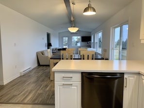 A modern kitchen with a central island, white cabinetry, and a stainless steel dishwasher.