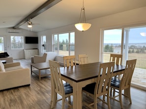 A spacious living area with a dining table and chairs, a sofa, and a television.