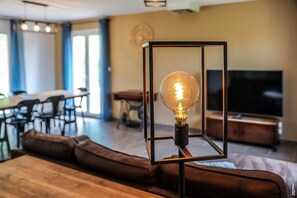 Una sala de estar moderna con un sofá de madera, una zona de comedor y una televisión.