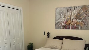 Un dormitorio con cama, mesita de noche, luz en la pared y una puerta.