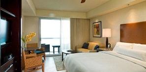 Une chambre d’hôtel avec un lit, un canapé, une télévision, une table et une chaise.
