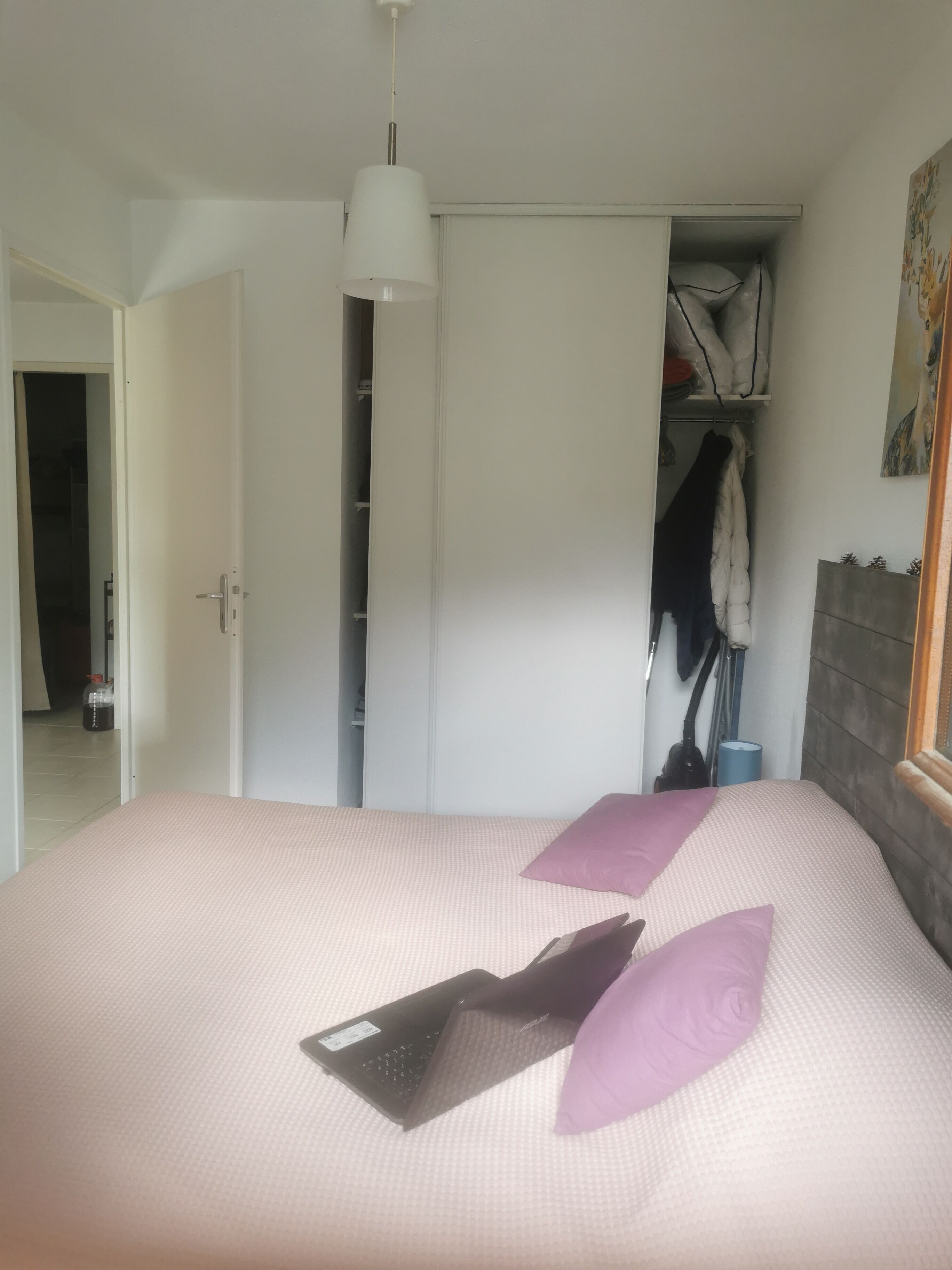 A bedroom with a bed, a closet, and a window.