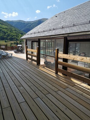 Una terraza de madera con sillones de descanso y vistas a una cadena montañosa.