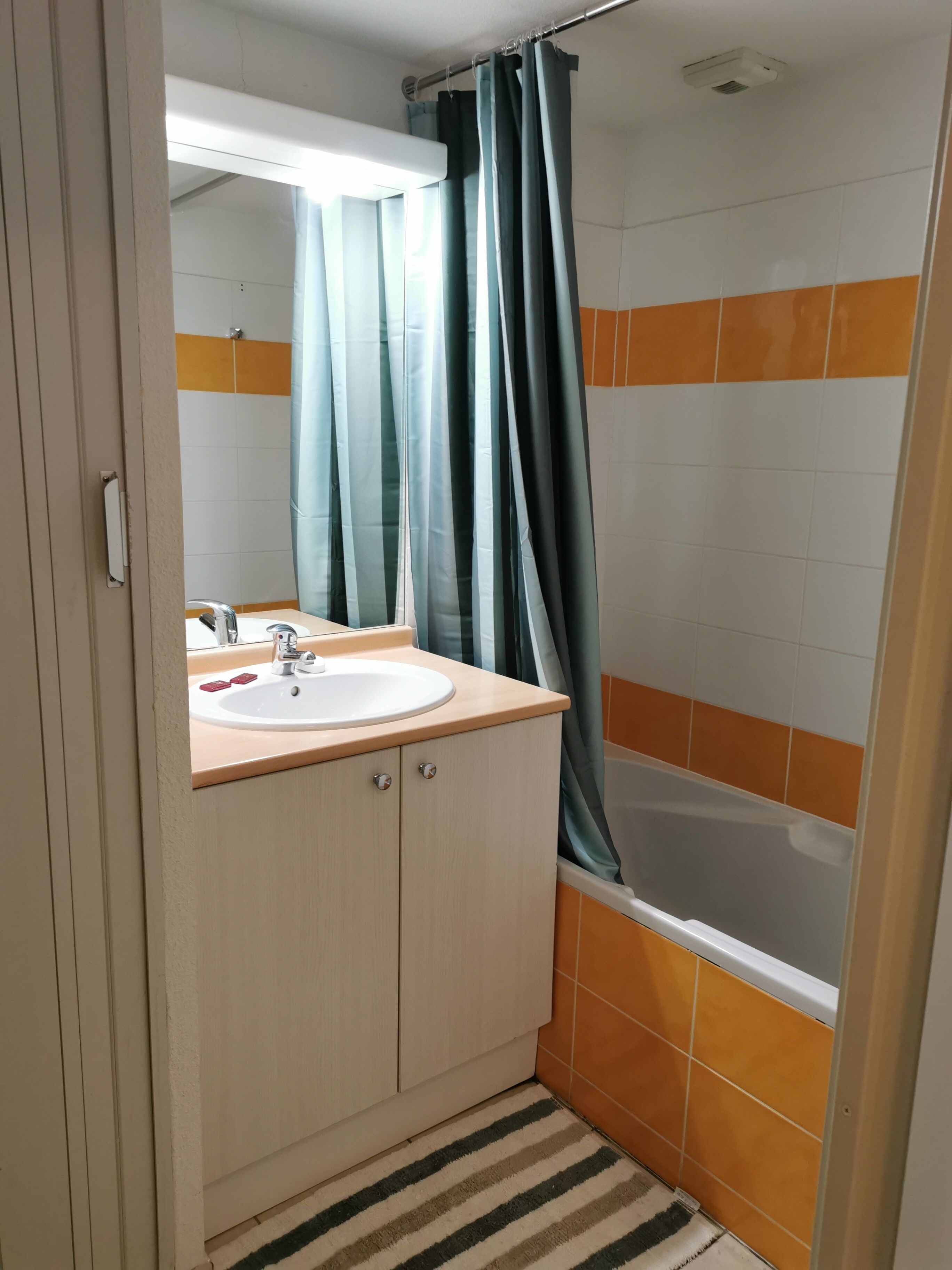 Une salle de bain avec un lavabo, un miroir et un rideau de douche.