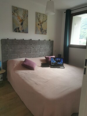 A bedroom with a bed, a laptop, and two paintings on the wall.