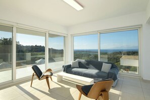A spacious balcony with a sofa and chairs, offering a panoramic view of the landscape.