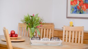 A dining table with a vase of flowers, a plate of apples, and a candle. - Reethus, 3 bedrooms + 1 infant, 2 bathrooms, fireplace, sauna, outdoor whirlpool, garden, WLAN (Seebad Heringsdorf)