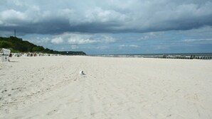 A wide sandy beach with footprints, a few people, and a lighthouse in the distance. - Reethus, 3 bedrooms + 1 infant, 2 bathrooms, fireplace, sauna, outdoor whirlpool, garden, WLAN (Seebad Heringsdorf)
