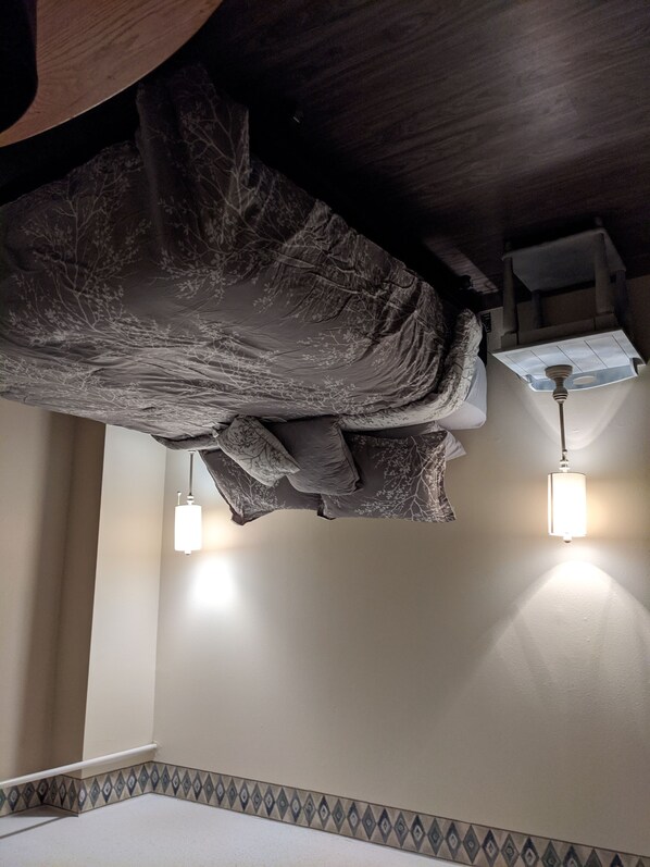 Un dormitorio con una cama, dos lámparas de noche, una mesita de noche y un borde decorativo en la pared.