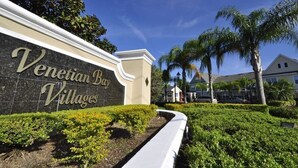 A sign for Venetian Bay Villages with a well-maintained hedge and palm trees in the background. - Perfect Family Vacation Spot close to major Orlando attractions! (Kissimmee)