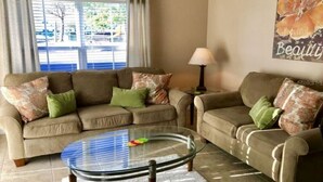 A living room with two sofas, a glass coffee table, and a lamp. - Perfect Family Vacation Spot close to major Orlando attractions! (Kissimmee)