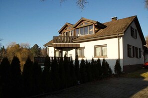 Ein zweigeschossiges Haus mit Balkon, großen Fenstern und einem Ziegelweg.