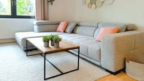 A modern living room with a grey sectional sofa, a wooden coffee table, and a small potted plant arrangement.