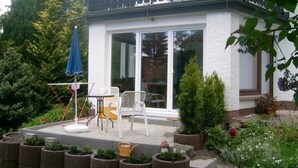 A patio with a table and chairs, surrounded by planters and a small garden.
