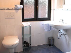 Ein Badezimmer mit Toilette, Waschbecken, Fenster und Handtuchhalter.