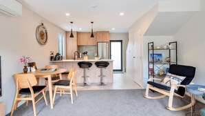 Een moderne keuken met houten kastjes, een centraal eiland met barkrukken en hanglampen.