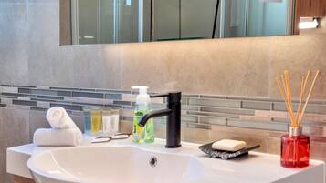 A modern bathroom with a white sink, a black faucet, a glass mirror, and a tiled backsplash.