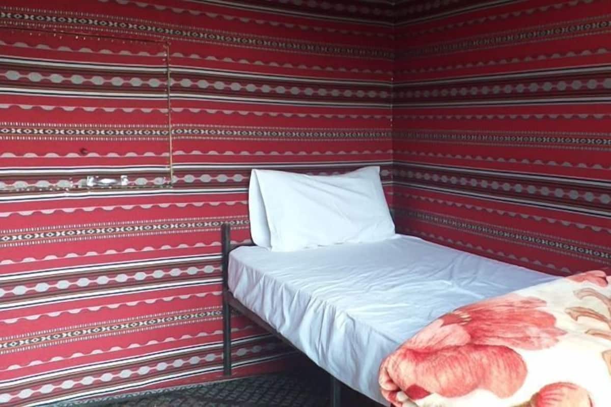 Une pièce avec un lit, un oreiller et un mur décoré de motifs.