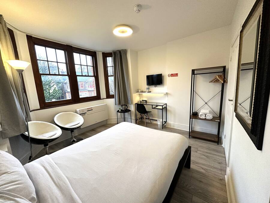 Een hotelkamer met een bed, een bureau, een stoel, een televisie en een kledingkast.