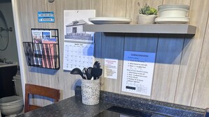 Ett kompakt kök med en bänkskiva i granit, en inbyggd spis, en diskho och ett litet skåp. På väggen finns skyltar som visar vilket Wi-Fi-nätverk som används och lösenordet för gästnätverket.