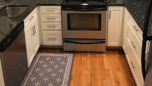 A modern kitchen with white cabinets, a stainless steel stove, a microwave, and a dishwasher. - The Pink Palace - Fenwick Island Beach Block w/ Pool & Super Easy Beach Access (Fenwick Island)